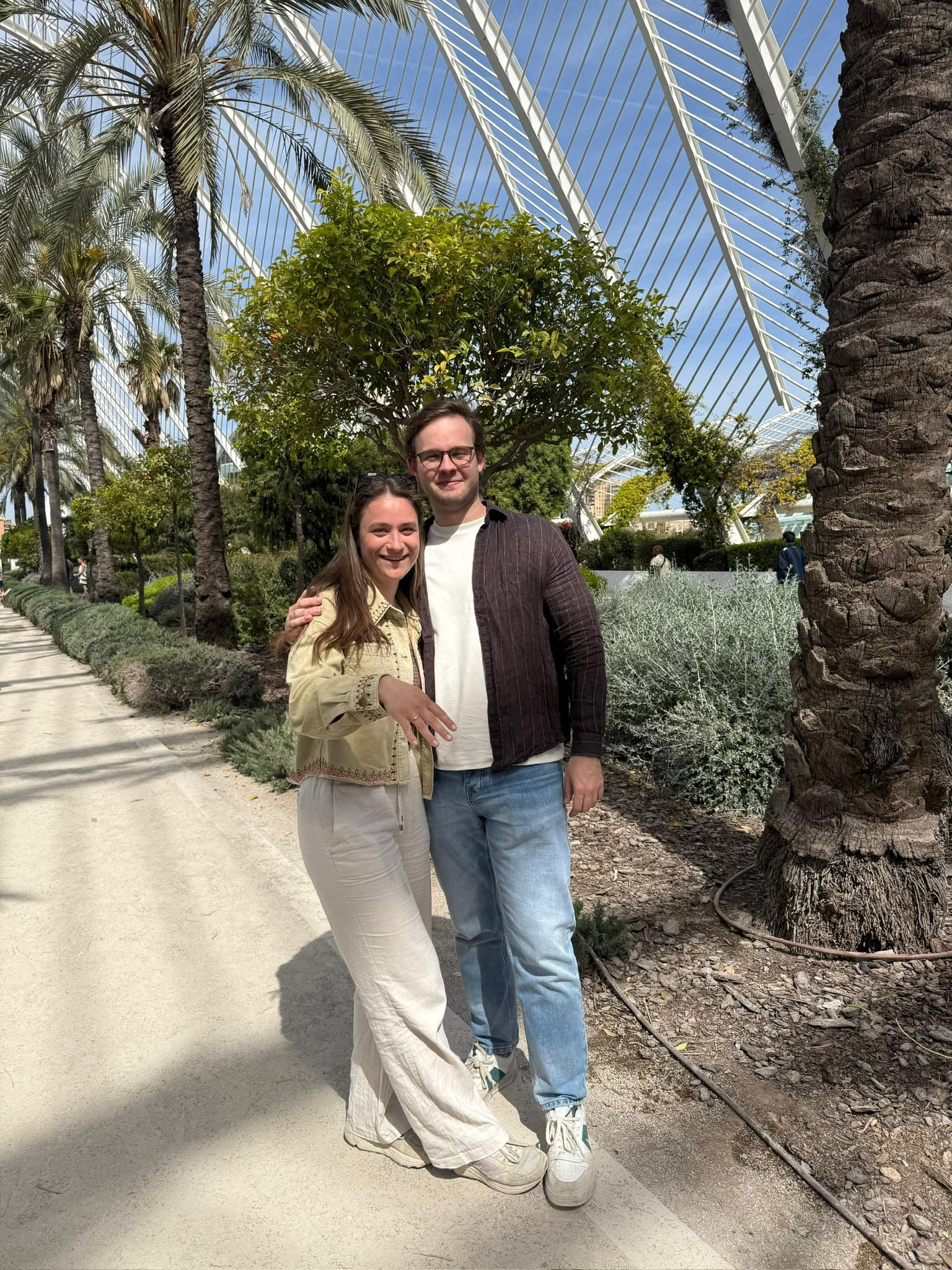 Mick en Eva samen in een plantentuin, Eva's hand met de ring in beeld